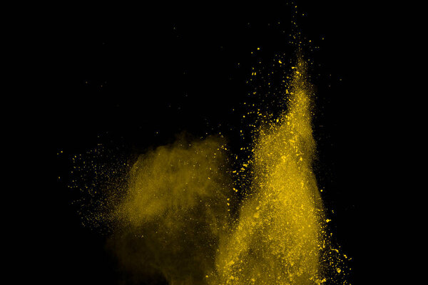 Yellow powder explosion on black background. Colored cloud. Colorful dust explode. Paint Holi.