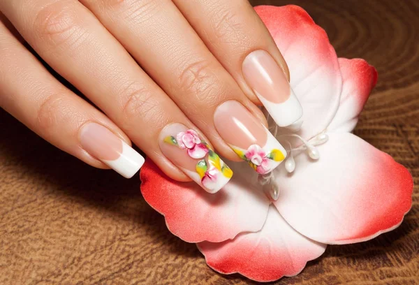 Mano femenina con manicura de uñas de arte y fondo de flores . — Foto de Stock