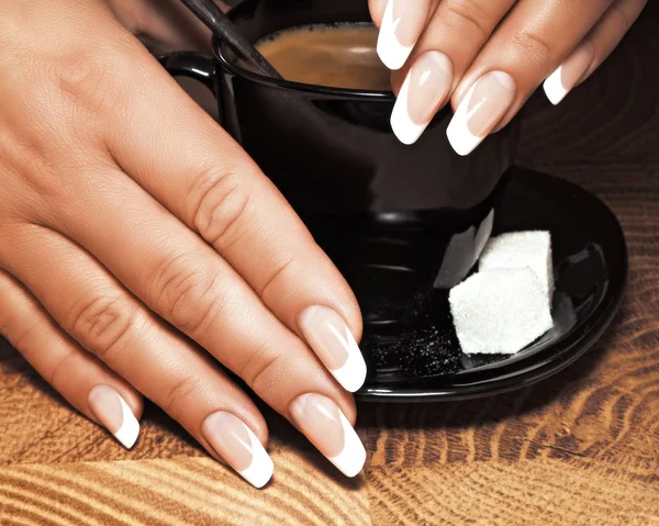 Le mani femminili con manicure tengono una tazza di caffè . Immagine Stock