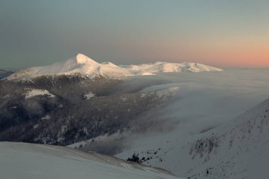 Kış dağının tepesinde yumuşak pembe gün batımı