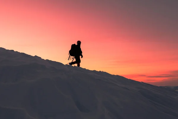 Un hombre desciende de la cima de la montaña al atardecer — Foto de Stock