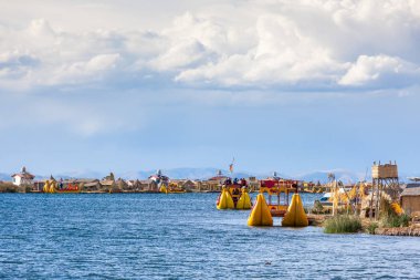 Floating islands of Uros, Lake Titicaca, Peru, South America - 2019-12-01. View of the island, a boat from the reeds, blue sky in the clouds. clipart