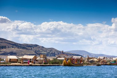 Güney Amerika, Titicaca Gölü 'nde yüzen Uros adaları - 2019-12-01. Adada yerli bir adam ve iki kadın var. Sazlıklı bir turist teknesinin yanında..