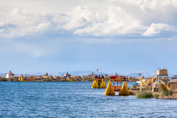 Uros adaları, Titicaca Gölü, Peru, Güney Amerika - 2019-12-01. Adanın manzarası, sazlıklardan gelen bir tekne, bulutlarda mavi gökyüzü.