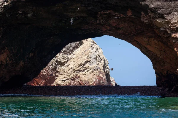 Grote grot met een strand, een zeeleeuw in het midden, vogels vliegen Ballestas Eilanden, Paracas Natuurreservaat, Peru, Latijns-Amerika. — Stockfoto