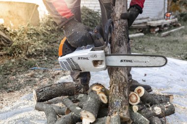 Kiev bölgesi, Ukrayna - 2019-10-05. Adam Stihl testeresiyle ağaç kesiyor, talaş her yöne uçuyor, yakın plan..