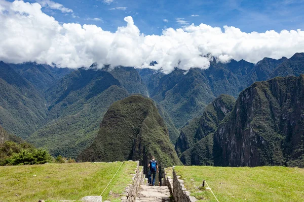 Muž sestupuje po kamenném schodišti, pozadí hor a oblohy v oblacích. Machu Picchu, Peru. — Stock fotografie