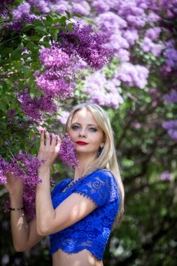 Çiçekli leylaklı güzel sarışın kameraya bakıyor, dikey yönelim..