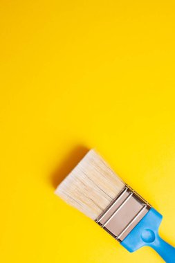Sarı arkaplanda boya fırçası, dikey yönelim, kopyalama yapıştırıcısı.