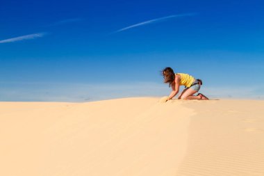 Kadın çöldeki bir tepede oturuyor.