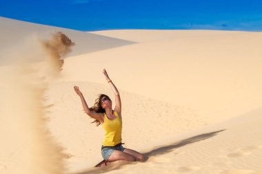 Kadın çölde kum atıyor.