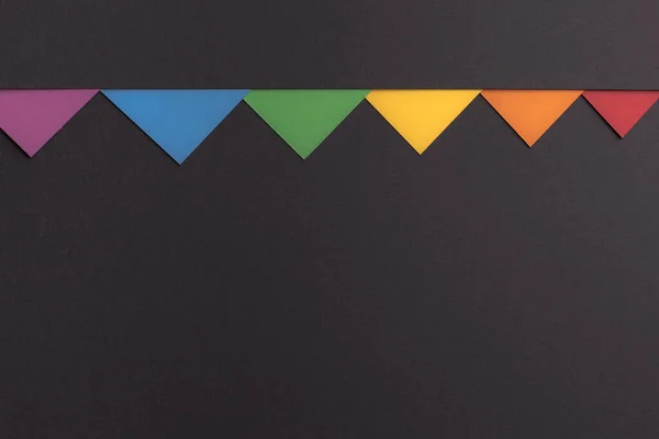 Pequenos triângulos multicoloridos em um fundo preto minimalista, espaço de cópia . — Fotografia de Stock
