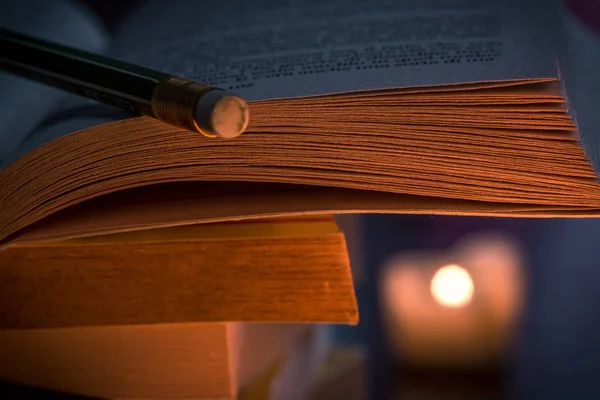 Boek en potlood in kaarslicht — Stockfoto