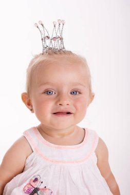 Mutlu gülümseyen çocuk beyaz arka planda bir stüdyoda oturuyor.