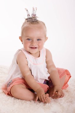 Mutlu gülümseyen çocuk beyaz arka planda bir stüdyoda oturuyor.