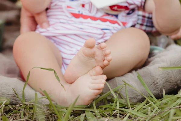 bare baby feet outside with green grass in a garden park