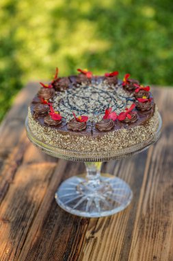 Kırmızı çiçekle süslenmiş çikolatalı pasta.