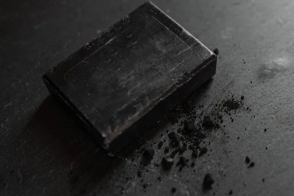 charcoal coal carbon black soap bar on a raw wood background lava stone spa skin care hygiene concept