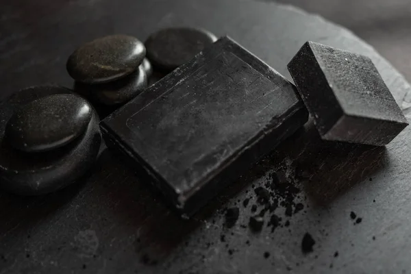 charcoal coal carbon black soap bar on a raw wood background lava stone spa skin care hygiene concept