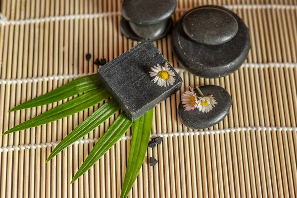 charcoal coal carbon black soap bar on a raw wood bamboo background lava stone spa skin care hygiene concept