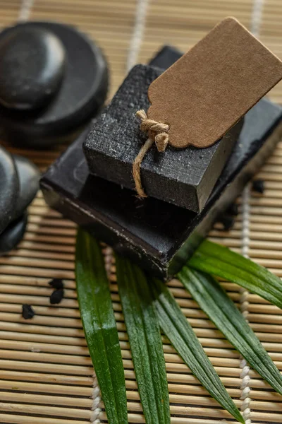 charcoal coal carbon black soap bar on a raw wood bamboo background lava stone spa skin care hygiene concept. black black stone backgroun. raw wood background lava stone spa skin care hygiene concept