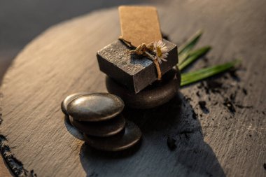 kömür kömürü karbon siyah sabun çubuğu çiğ ahşap bambu arkaplan lav taşı kaplıca cilt hijyen konsepti. Siyah siyah taş sırtüstü. Çiğ ahşap arka plan lav taşı kaplıca cilt hijyen konsepti
