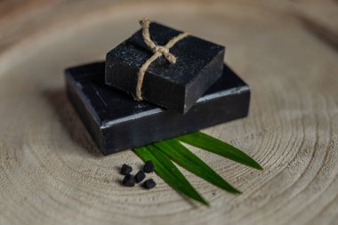 kömür kömürü karbon siyah sabun çubuğu çiğ ahşap bambu arkaplan lav taşı kaplıca cilt hijyen konsepti. Siyah siyah taş sırtüstü. Çiğ ahşap arka plan lav taşı kaplıca cilt hijyen konsepti