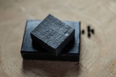kömür kömürü karbon siyah sabun çubuğu çiğ ahşap bambu arkaplan lav taşı kaplıca cilt hijyen konsepti. Siyah siyah taş sırtüstü. Çiğ ahşap arka plan lav taşı kaplıca cilt hijyen konsepti