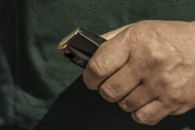 Şarjörde 9 'a 19' luk tabanca mermilerini dolduran bir adam atış poligonunda hobi olarak ateş ediyor. .