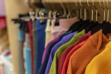 Parlak renkli elbiseler bir rafçı dükkanında satılıyor. 