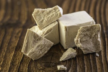 Beyaz bir mutfak zemininde ahşap oklamalı kuru ve taze bir maya.