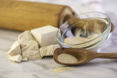 Beyaz bir mutfak zemininde ahşap oklamalı kuru ve taze bir maya.