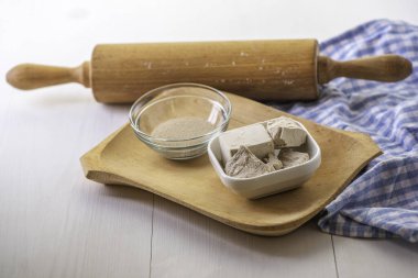 Beyaz bir mutfak zemininde ahşap oklamalı kuru ve taze bir maya.