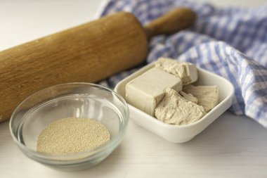 Beyaz bir mutfak zemininde ahşap oklamalı kuru ve taze bir maya.