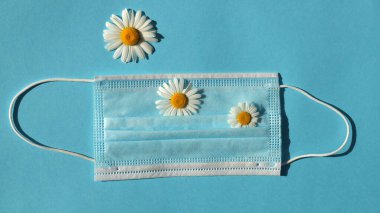 Mavi arka planda papatya çiçekli tıbbi maske