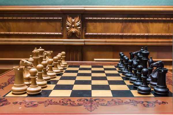 Деревянные шахматные фигуры на открытой шахматной доске в солнечный день, король в фокусе — стоковое фото