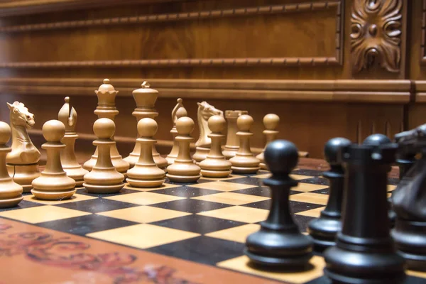 Черные фигуры на шахматной доске перед белыми фигурами — стоковое фото