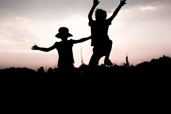 Kinderen springen van een rots bij zonsondergang — Stockfoto