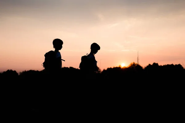 Silhouetten van kinderen wandelen bij zonsondergang — Stockfoto