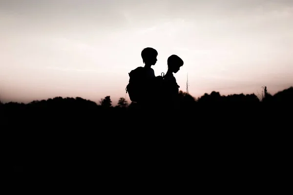 Siluetas de niños haciendo senderismo al atardecer —  Fotos de Stock