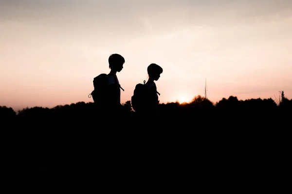 Silhuetas de crianças caminhadas ao pôr do sol — Fotografia de Stock