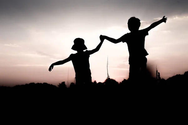 Kinderen springen een heuvel verhogen handen omhoog — Stockfoto
