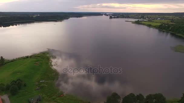 Een zicht vanuit de lucht op een rustig meertje. Zomer, groene oevers, wolken worden doorgevoerd. — Stockvideo