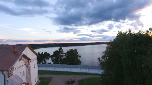 Luchtfoto van een schilderachtige oude klooster gelegen op de oever van het meer op de uitstekende lucht en de wolken bij zonsondergang — Stockvideo