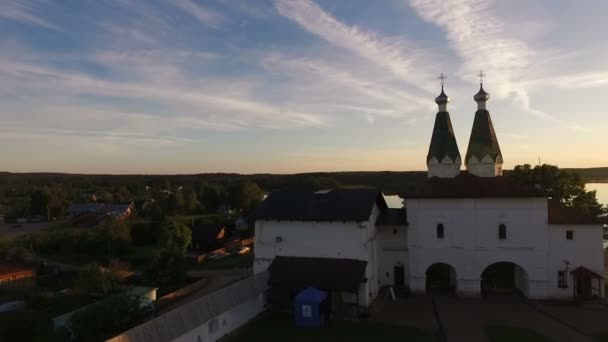 Вид с воздуха на живописный древний монастырь на берегу озера на прекрасном небе и облака на закате — стоковое видео