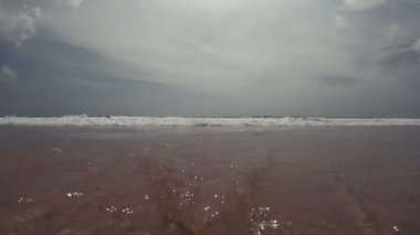 Kamera kabarcıkları ile kum üzerinde gelen dalga girer, suda bir deniz yosunu ip Sallanır