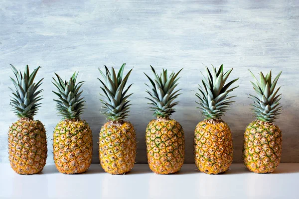 Ripe pineapples on white wooden background