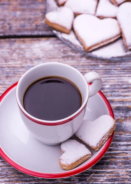 Coffee cup and biscuits, cookies in the shape of heart on wooden background — Stock Photo, Image