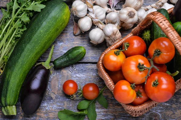 Овощи для сбора урожая: помидоры, огурцы, цуккини, баклажаны, лук, чеснок, руккола на деревянном фоне — стоковое фото