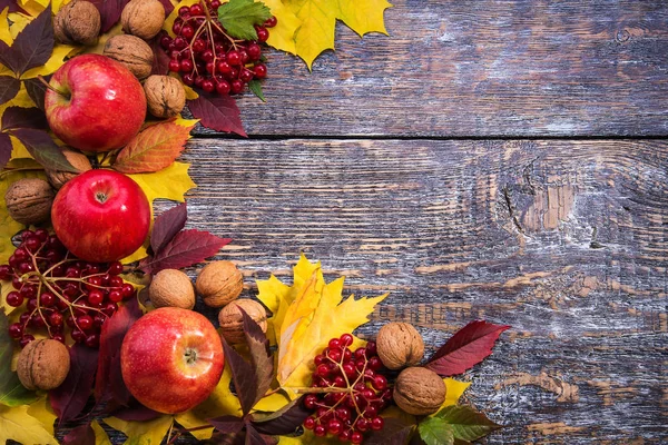 Folhas de outono, nozes, maçãs, viburno vermelho em um fundo velho de madeira. Vista superior — Fotografia de Stock